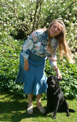 Foto - Rita Skov i haven sammen med frerhunden - foran et blomstende bletr